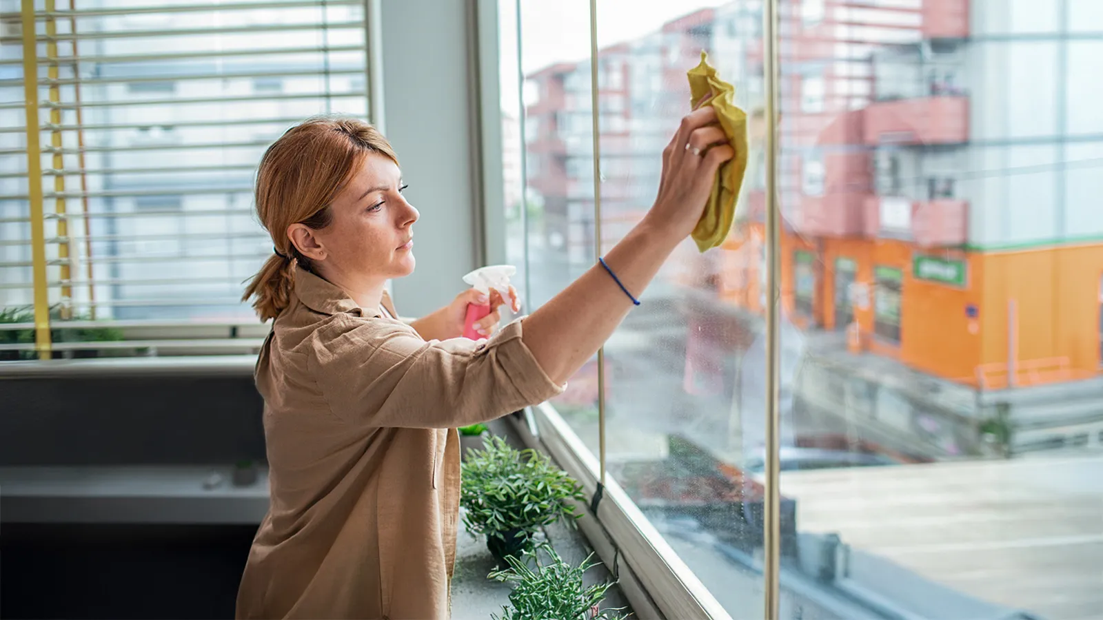 Frau putzt eine Fensterscheibe